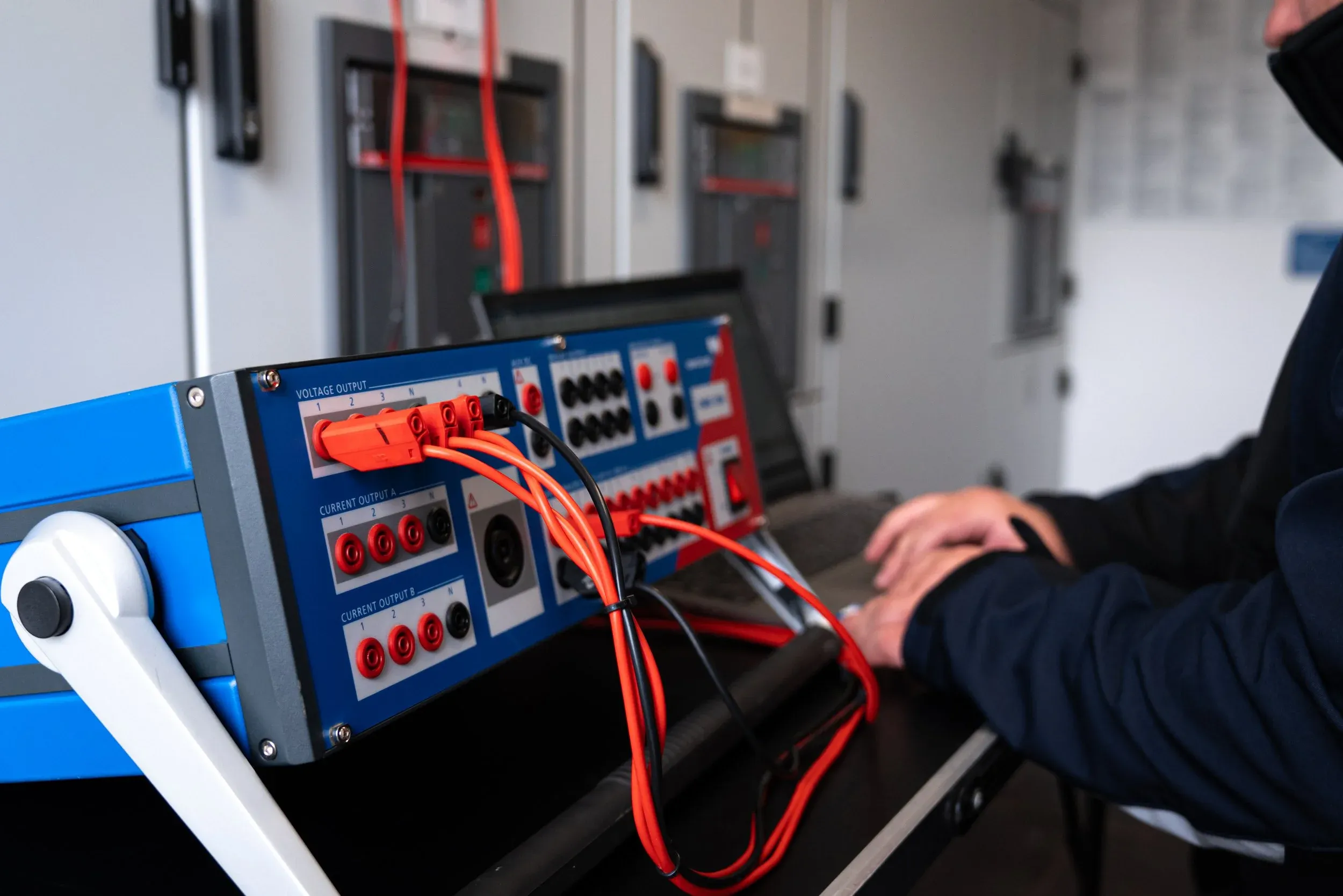 Mann verkabelt Prüfgerät für elektrische Messungen im Technikraum.