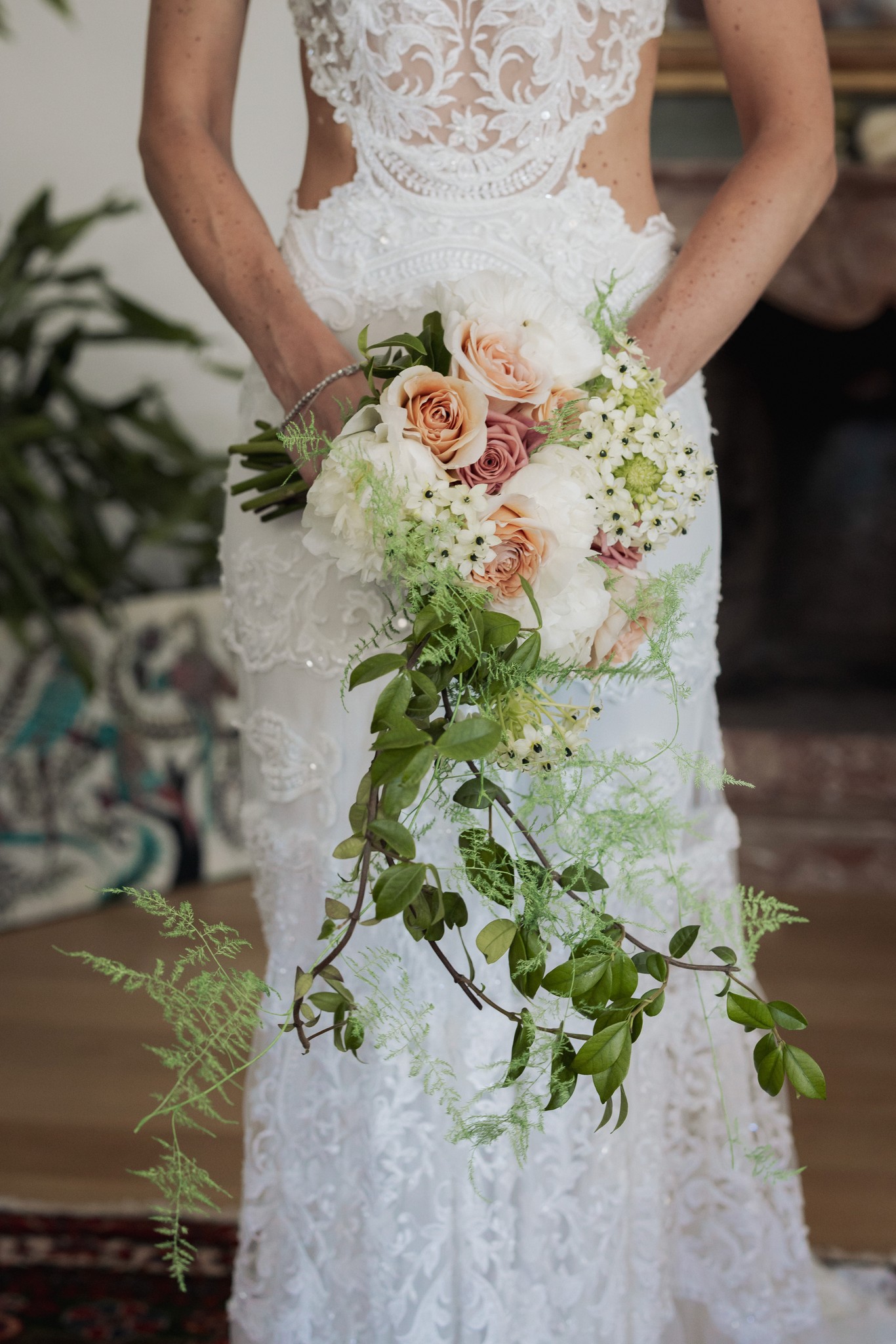 Sposa in abito di pizzo bianco con bouquet di rose pesca, ortensia e fogliame alla Rocca di Soragna