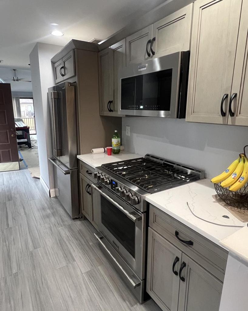 Gray shaker kitchen with a stainless gas range and quartz countertops