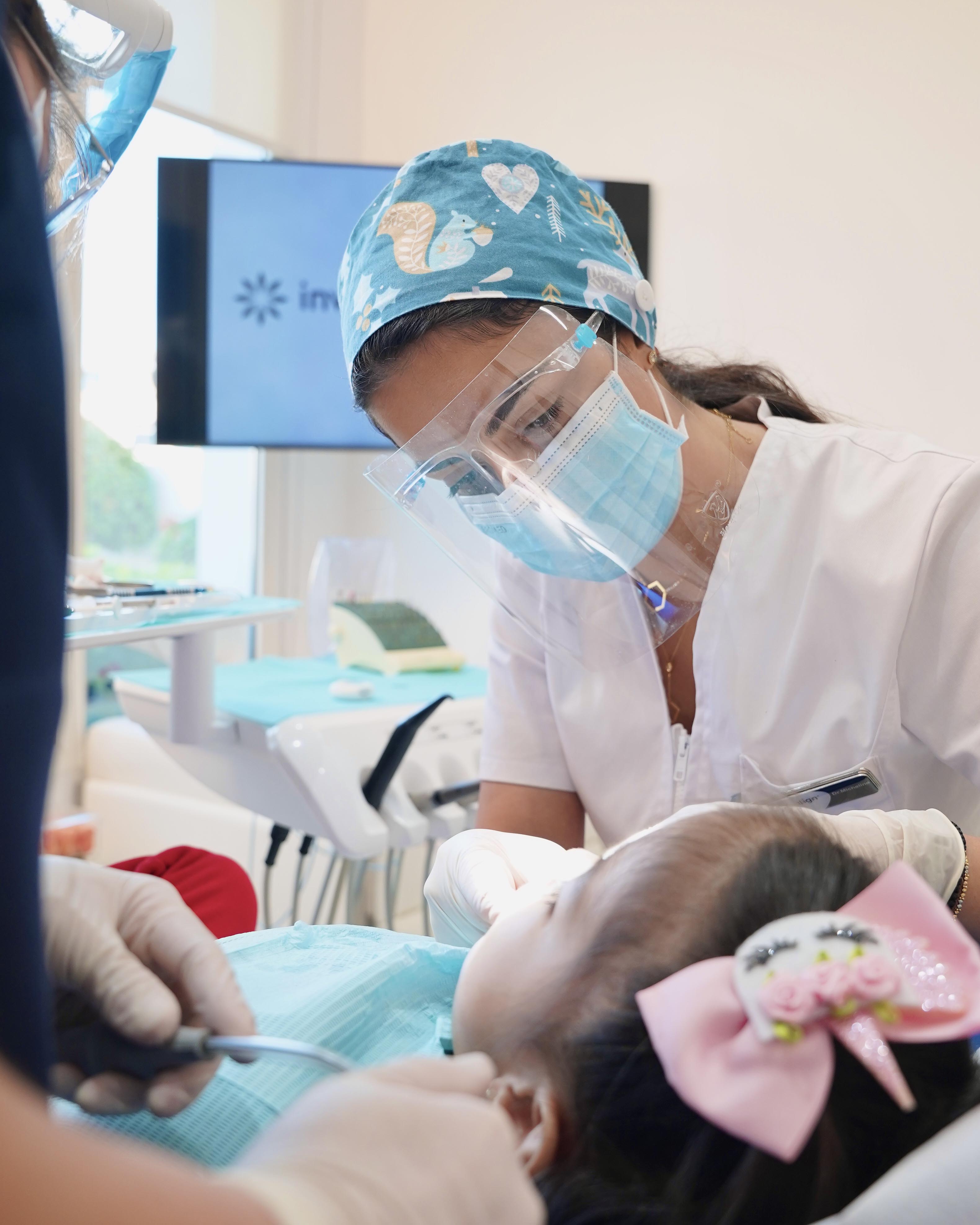 A pediatric dentist carefully examining a kid’s teeth at Invisalign Center