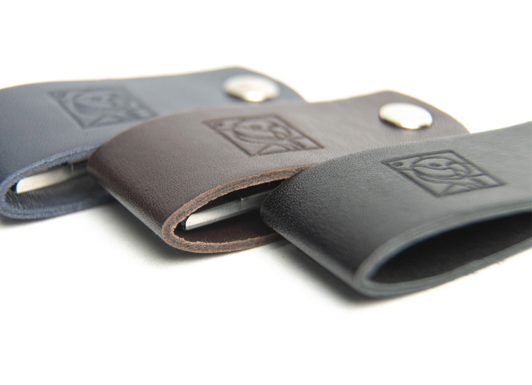 Three leather USB holders lined up in blue, brown, and black, displaying the folded loop design.