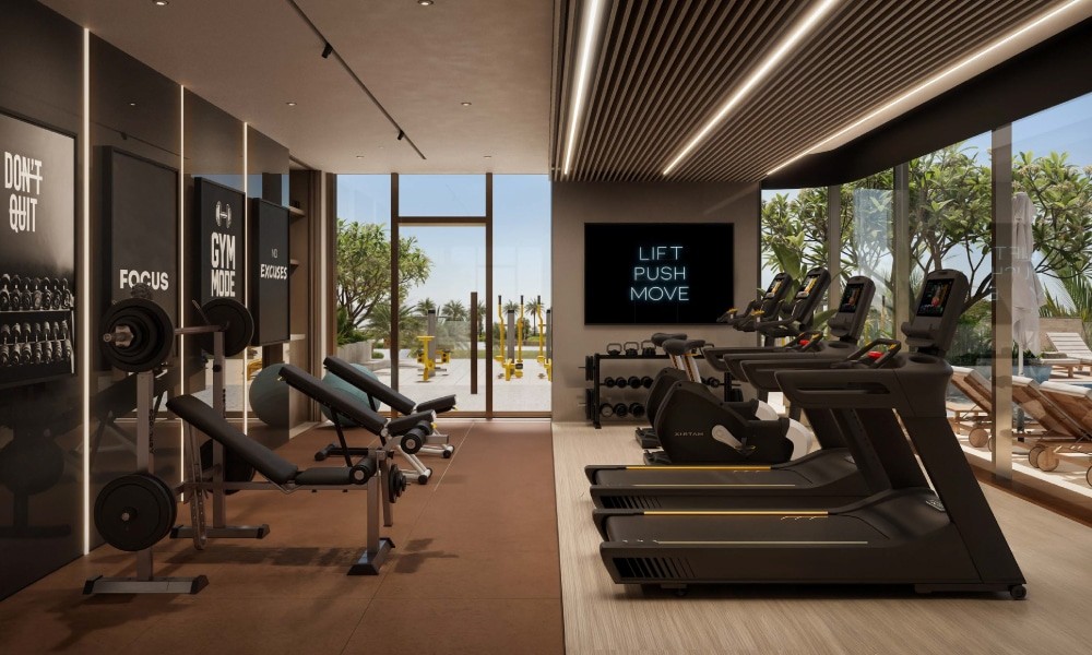 Interior of a gym at Flora Shore Beachfront Residences, showcasing exercise equipment and a spacious window.