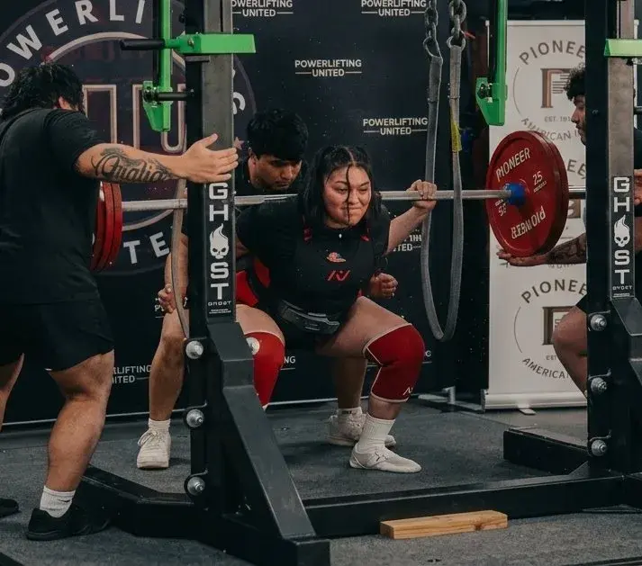 Female athlete squatting in the Big Tex Gym competition monolift