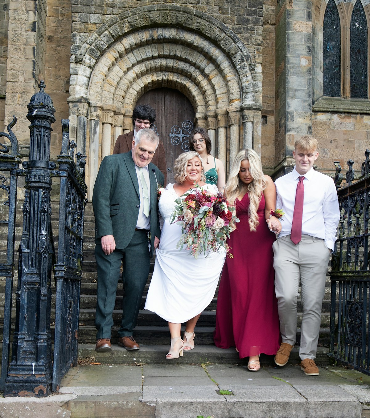 A bride and her family walking out through a Romanesque church doorway