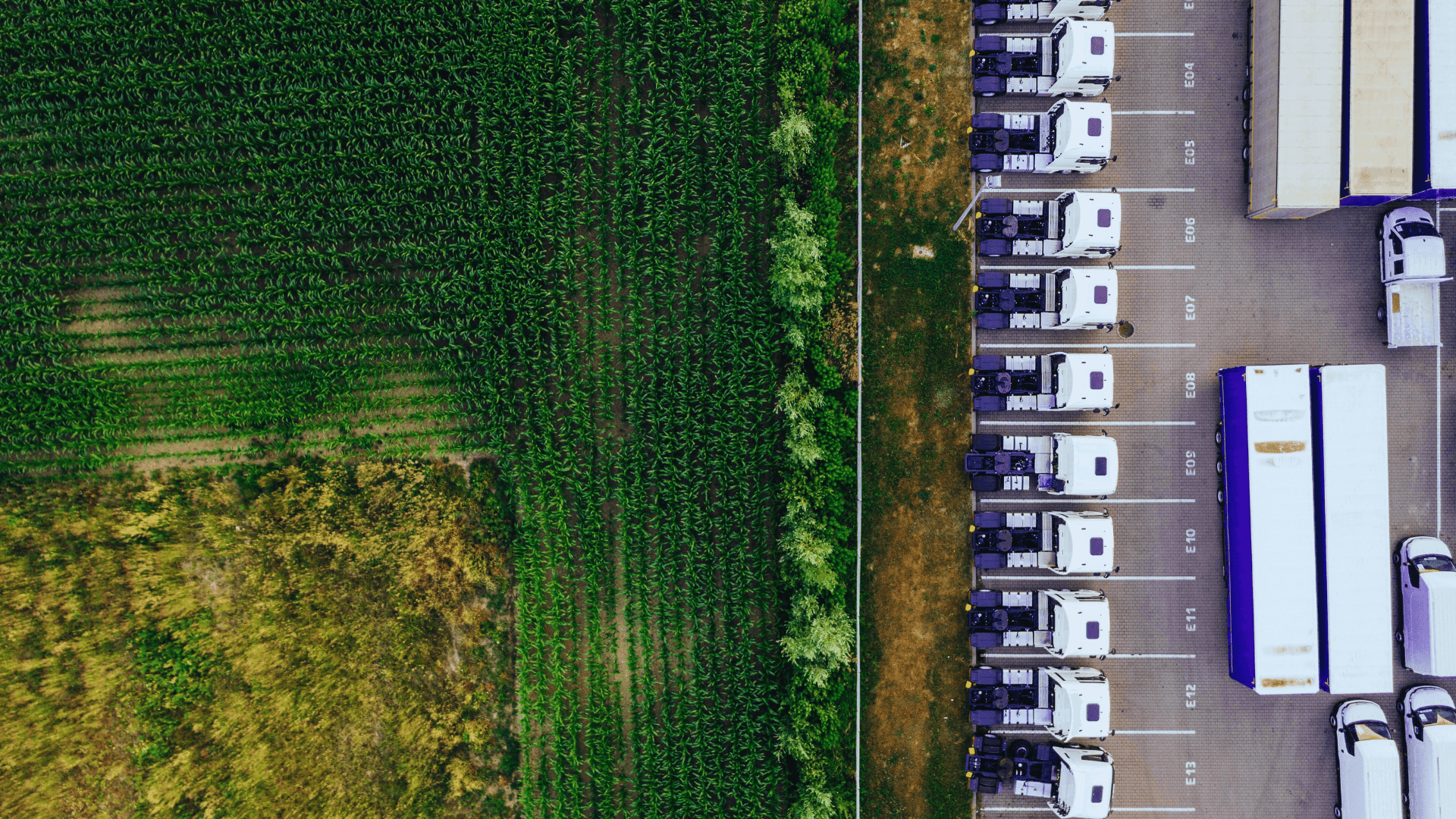 The environmental impacts of imports and exports within the framework of EU CBAM; an aerial view of a large truck parking area and agricultural land.