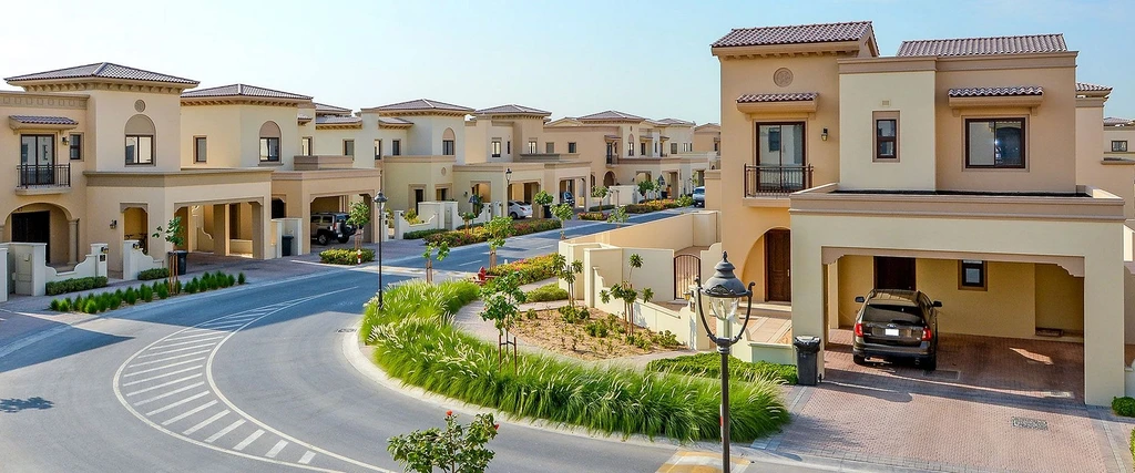 Scenic view of Arabian Ranches with white buildings and lush greenery, set against a backdrop reminiscent of Santorini.