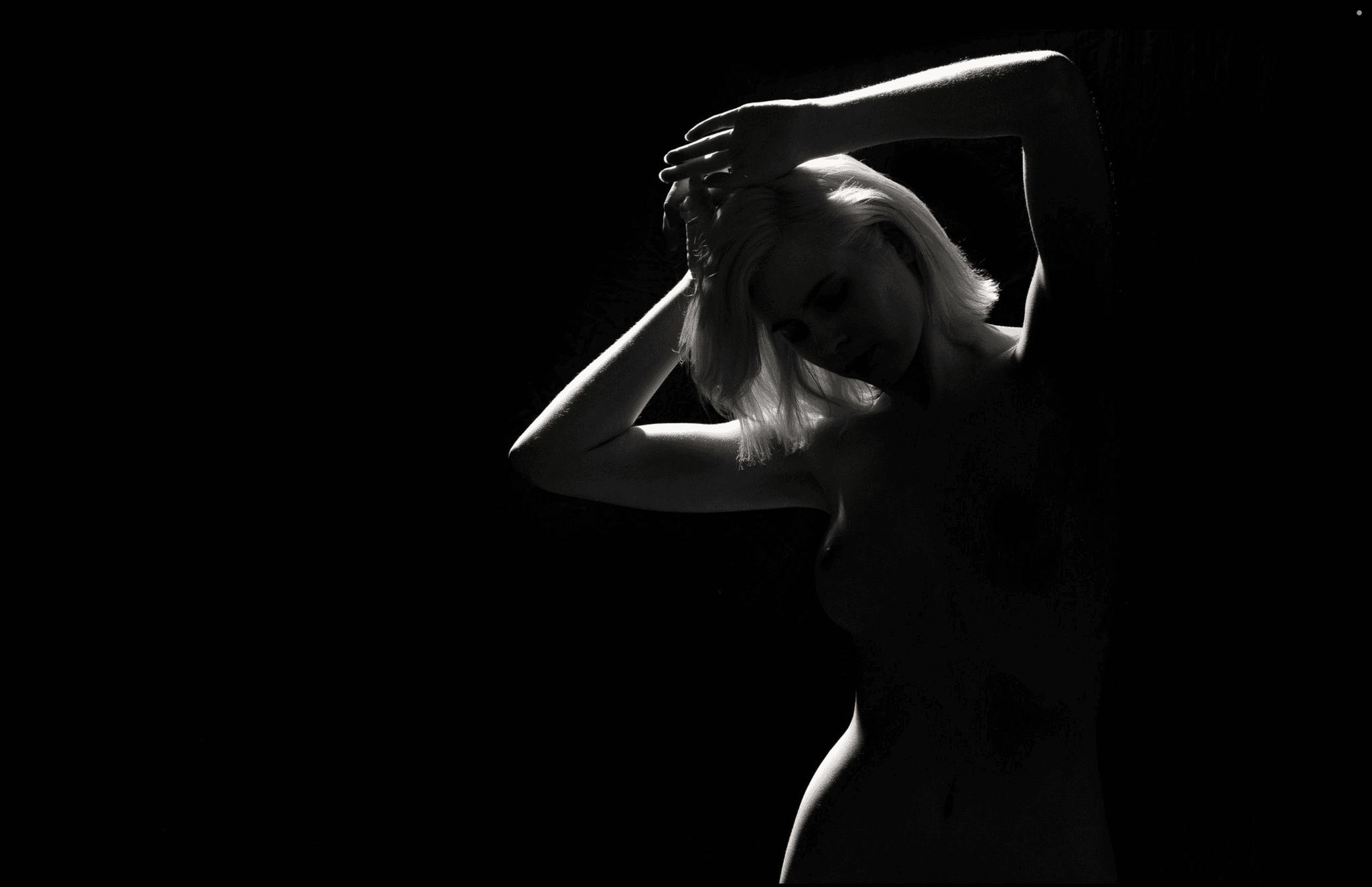 A still body of water with mountains in the background at sunset