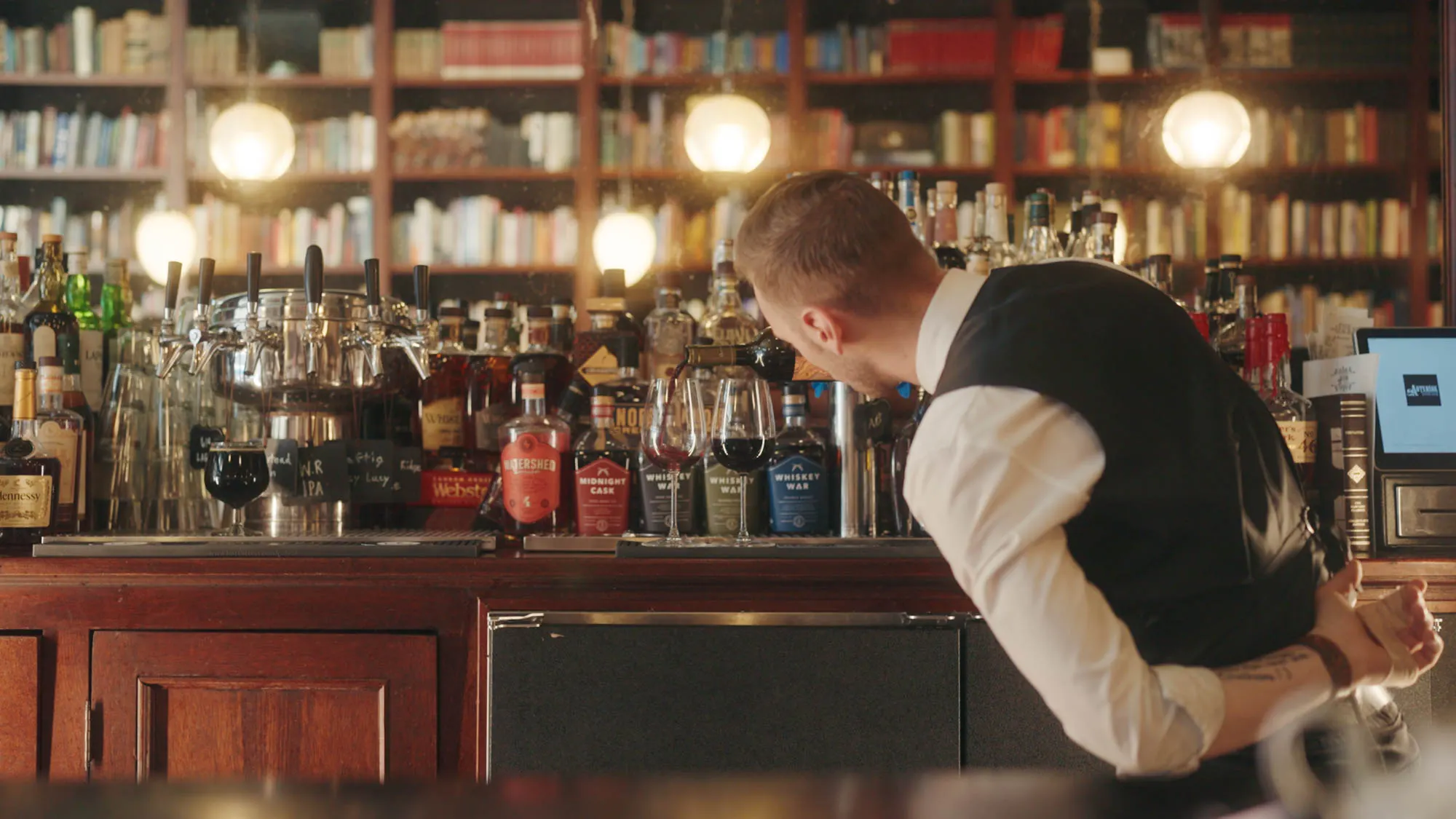 Back bar with bottles and bookshelves at Asterisk