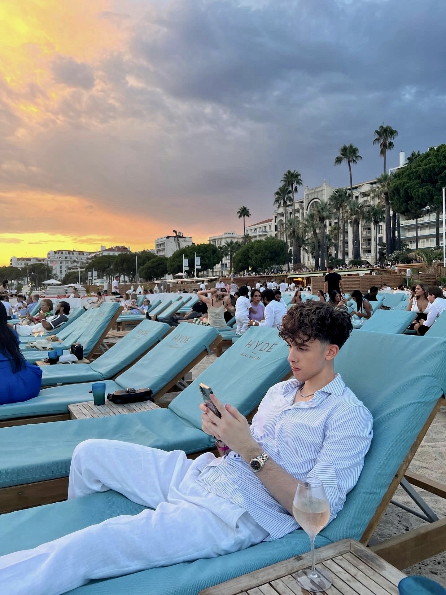 An ostrich is peeking at a man who is reading a newspaper.
