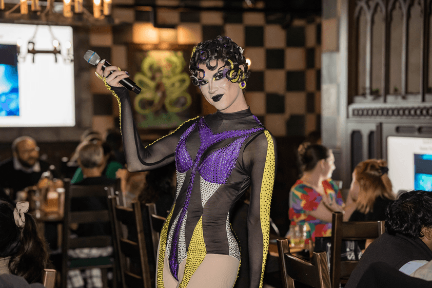 Drag queen Trinket hosting trivia in tavern posing to camera