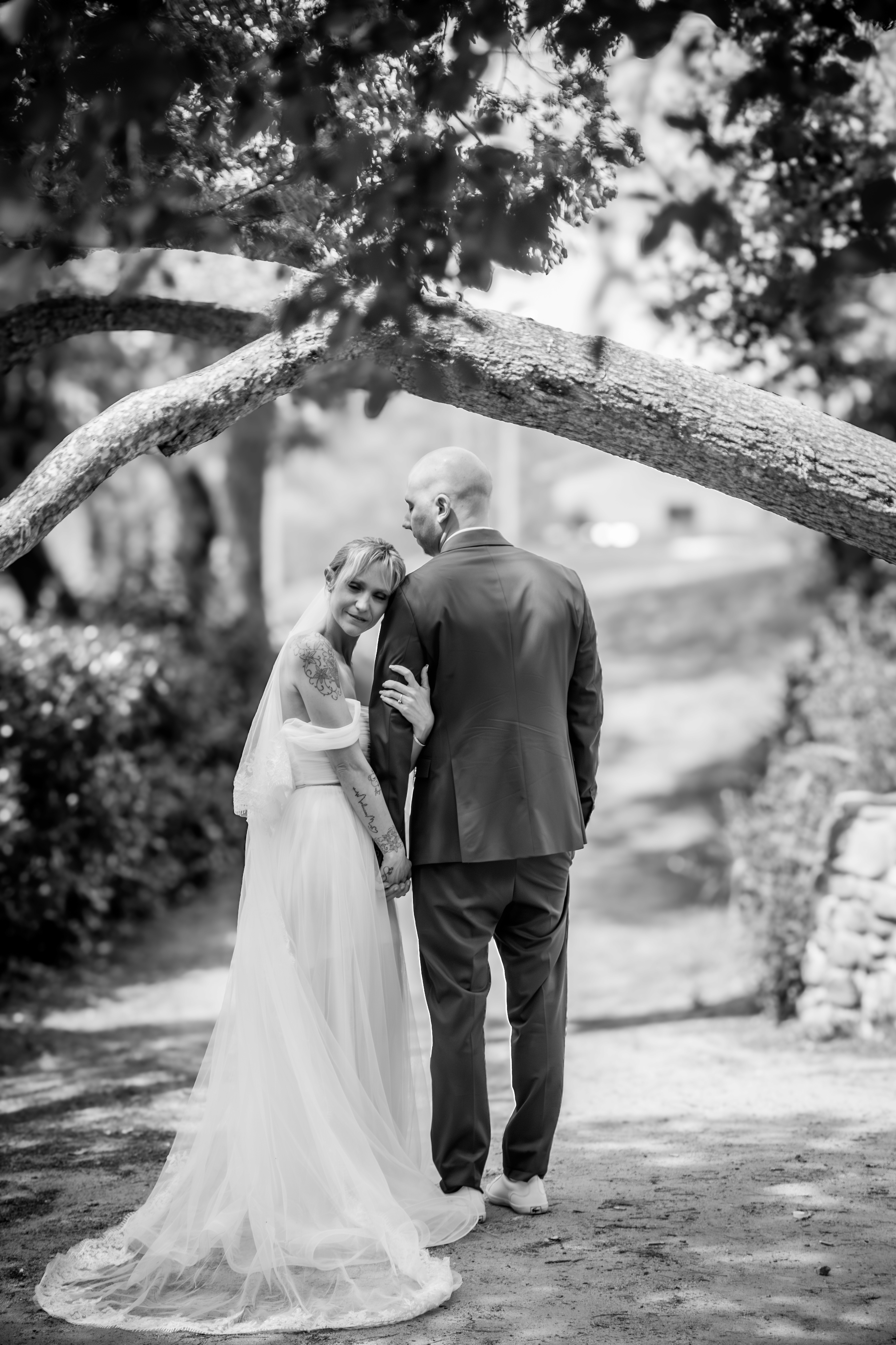 Sesión de boda en blanco y negro donde la pareja esta debajo de una rama. Ella esta posada en su hombro