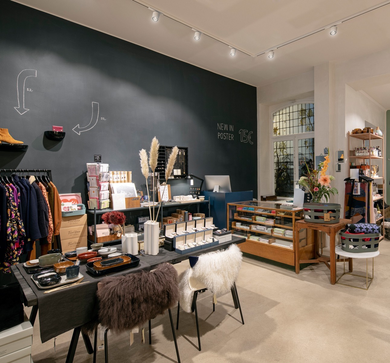 Modern glass and steel building with warm wooden ceilings, surrounded by lush greenery, blending contemporary architecture with nature.