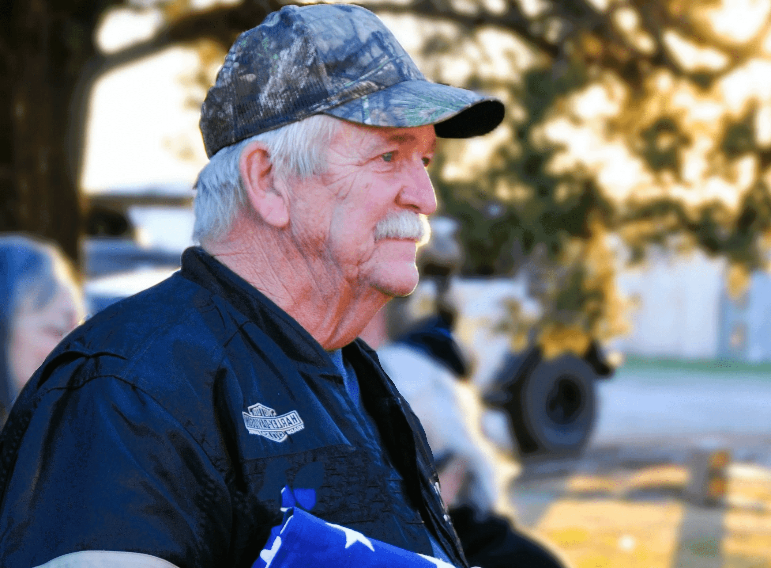 A man in a black jacket holding an american flag