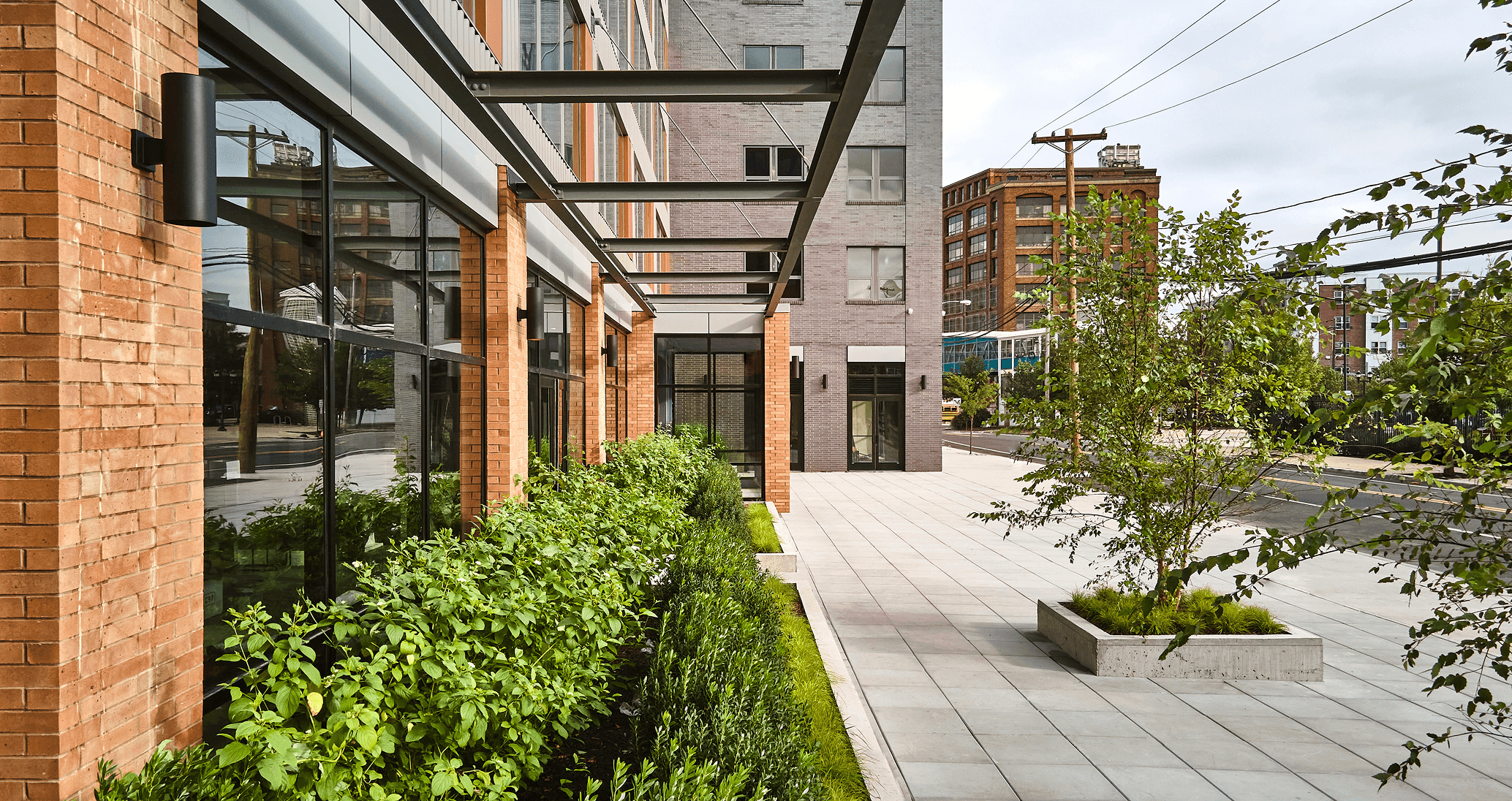 A modern building with large windows beside landscaped greenery and a paved walkway.