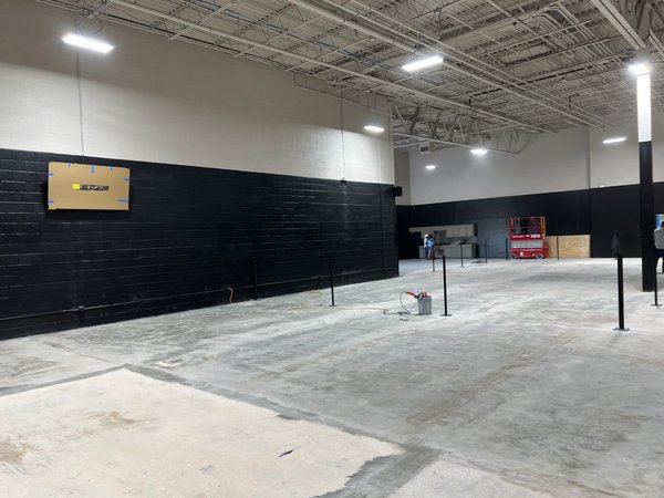 Concrete surface preparation and net post installation during indoor tennis court build out