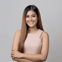 Smiling woman with long brown hair wearing a tan sleeveless top.