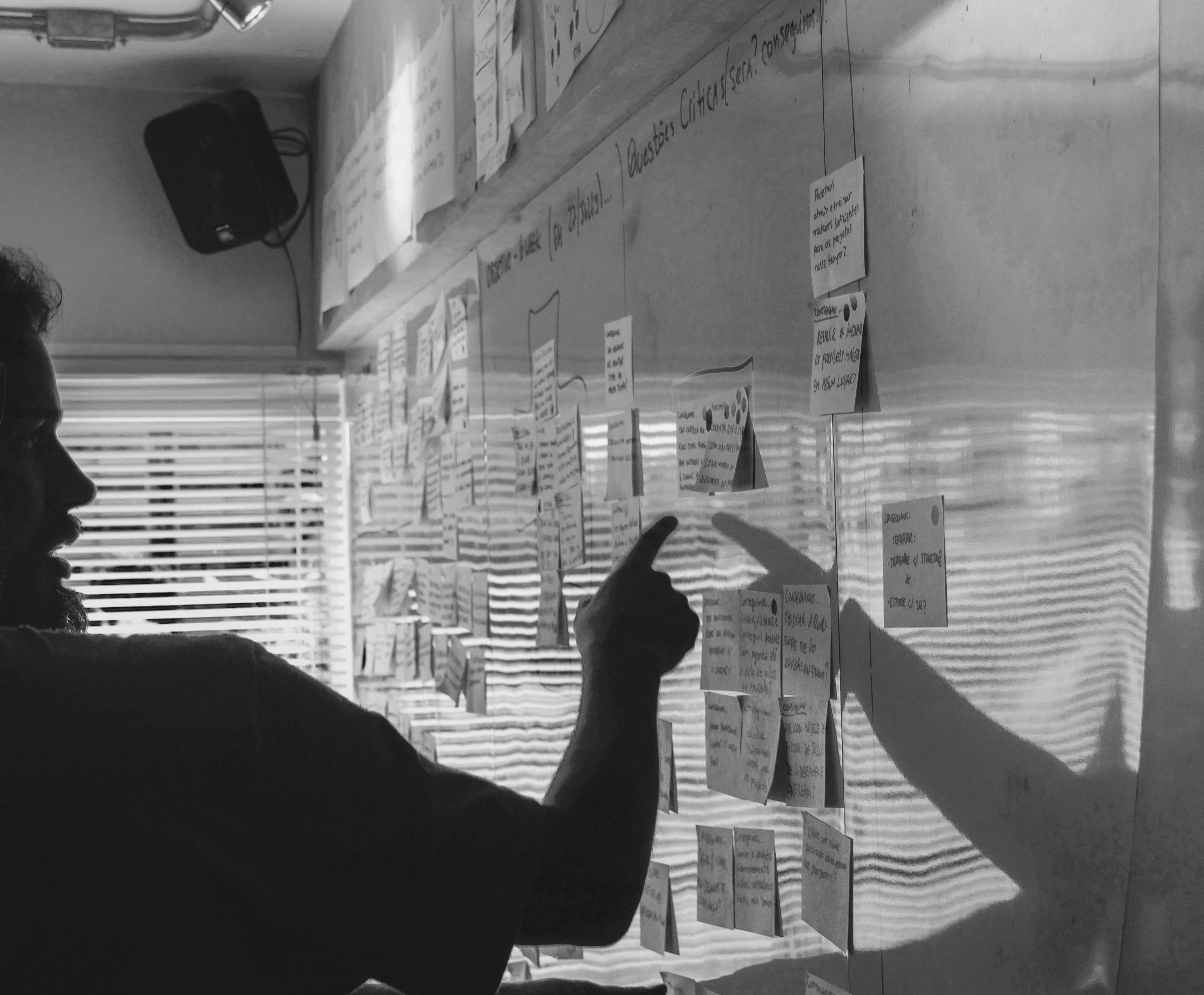 A black-and-white image of two silhouettes reaching toward each other, with their hands near a reflective surface.