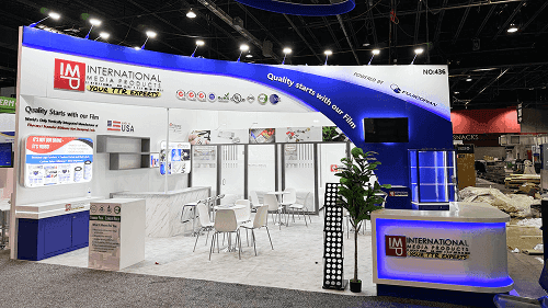 20x20 trade show booth with screen wall, branded hanging sign, meeting zone, lounge seating, and product presentation area