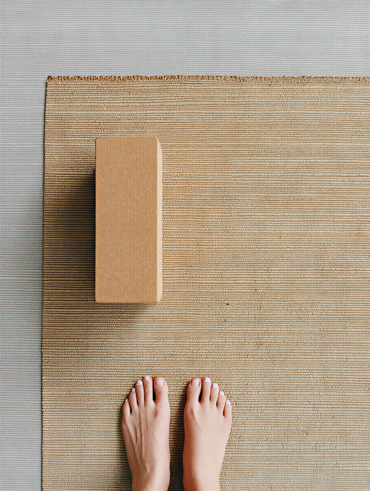 Bare feet at the end of a woven mat with a cork block