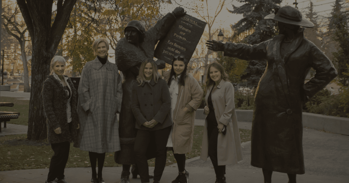 Image of Women in coats standing beside statues in a park, symbolizing empowerment and equality in KHD Homes community.