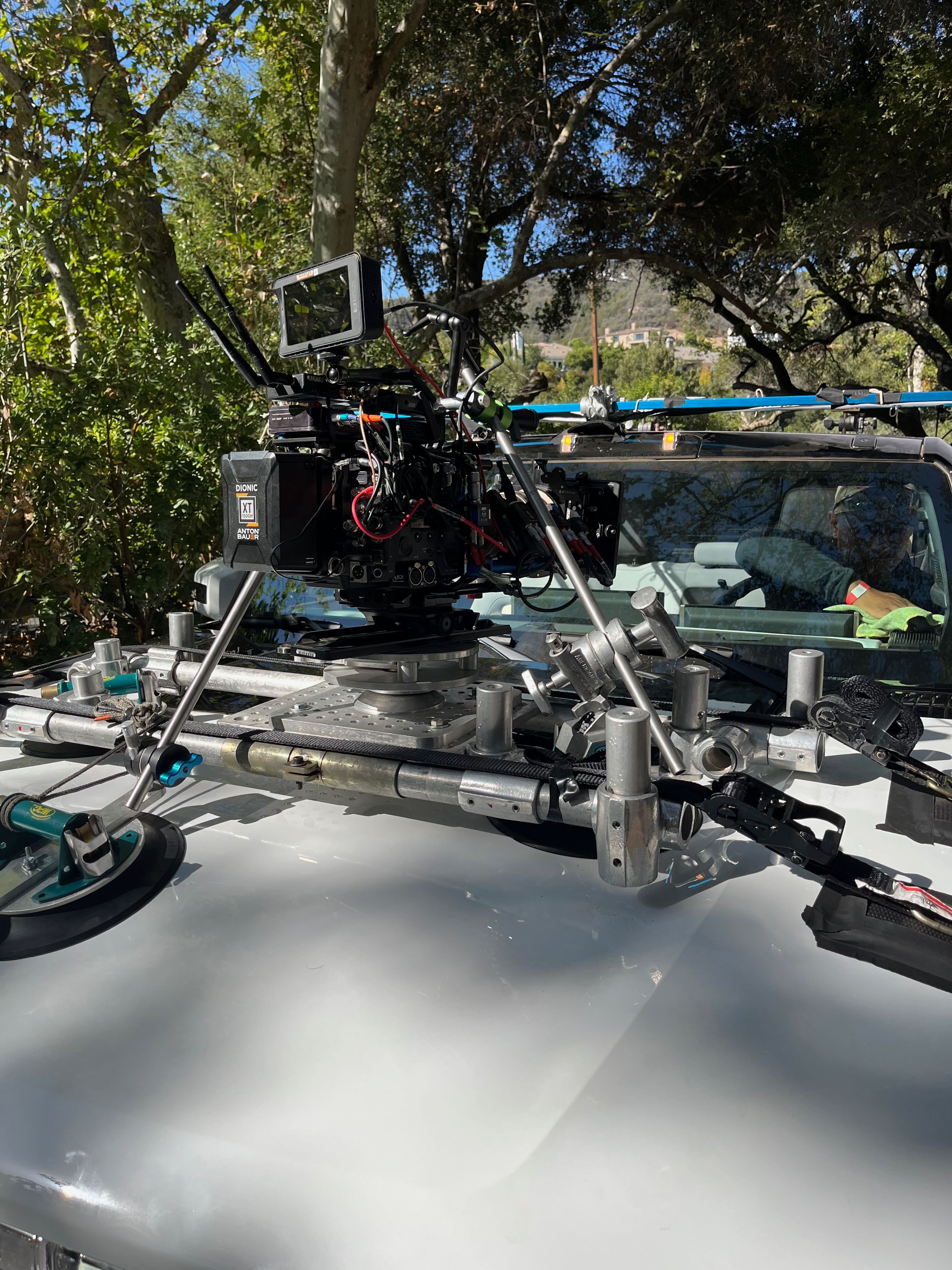 Cinema camera and monitor on a braced speed-rail hood mount in front of a white vehicle’s windshield