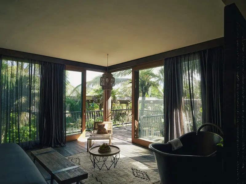 Ocean Suite en Be Tulum con amplias ventanas, vistas al océano y la jungla, y zona de estar cómoda.