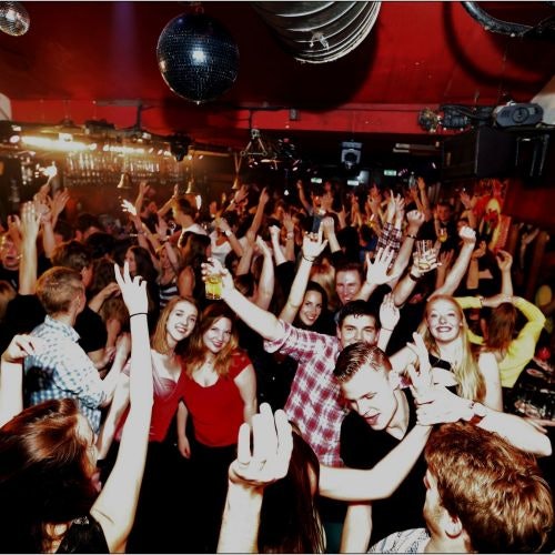 一大群人在拥挤的夜总会里跳舞和开心玩耍，头顶上是五光十色的灯光和迪斯科球。