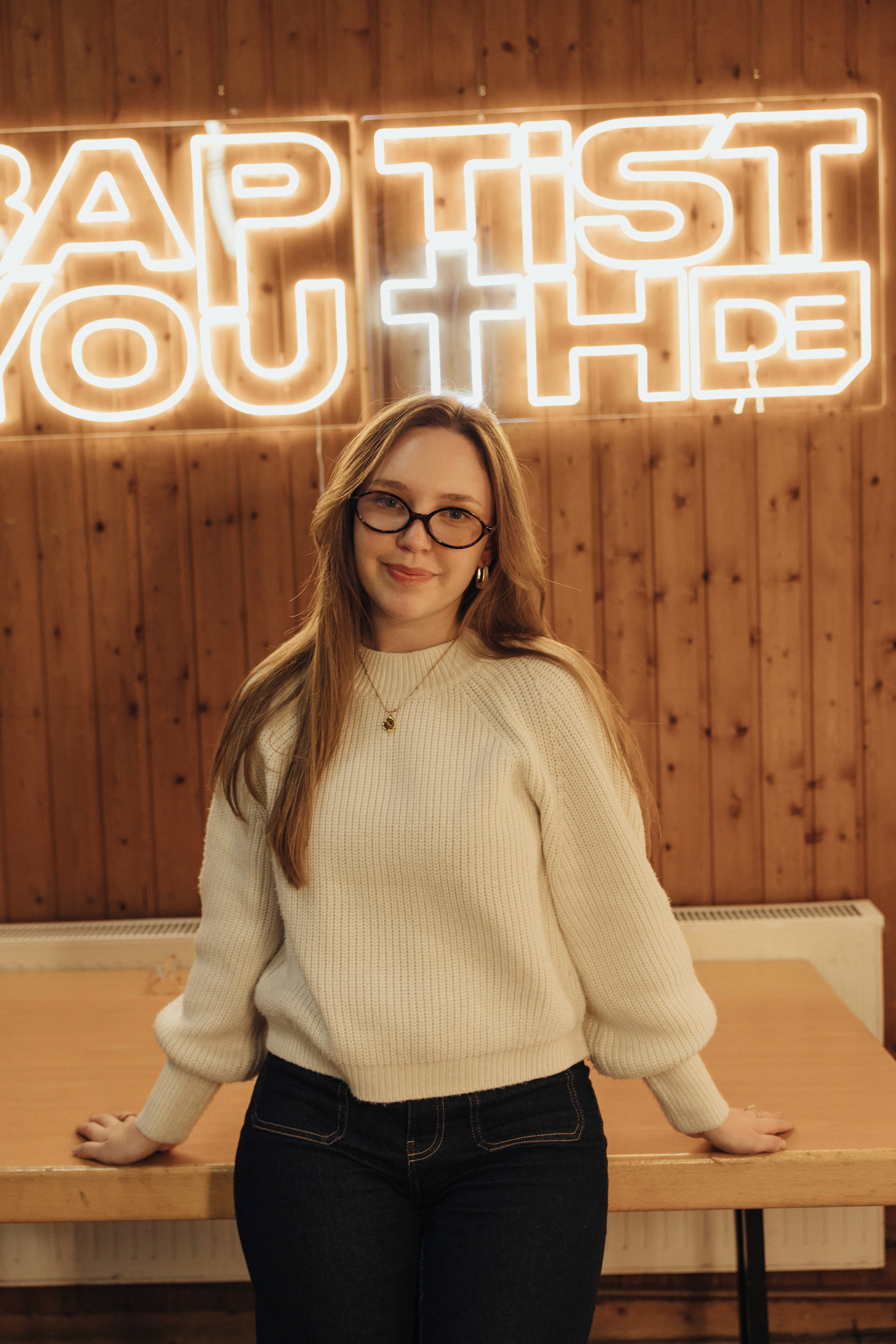 A thoughtful young person with dark hair gazes to the side, captured in soft black and white lighting.