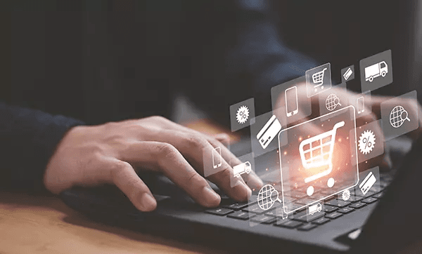 A person working on their home office desk with their headphones on. The lighting is dark with subtle,soft lights coming from a lamp