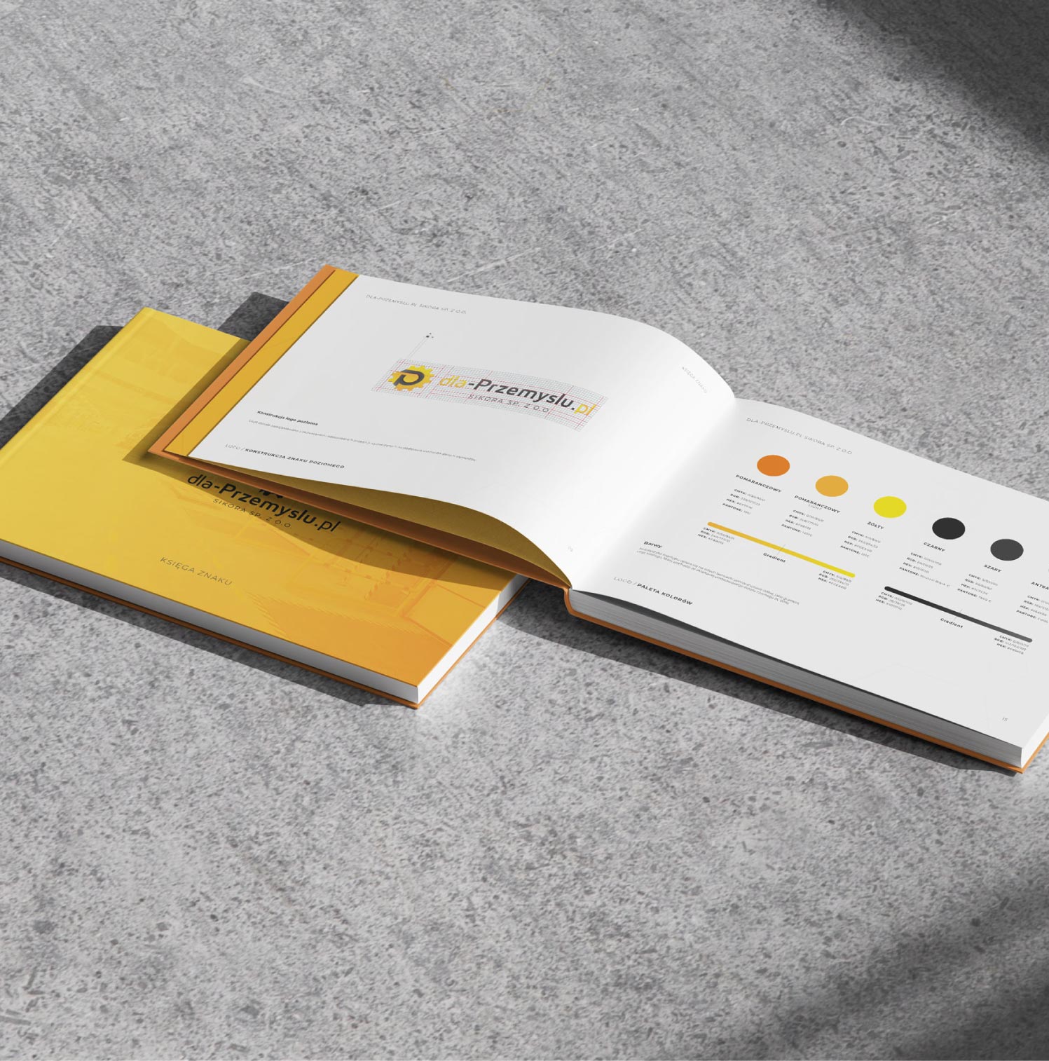 Otwarta i zamknięta drukowana księga znaku dla marki przemysłowej leżąca na betonowym podłożu.