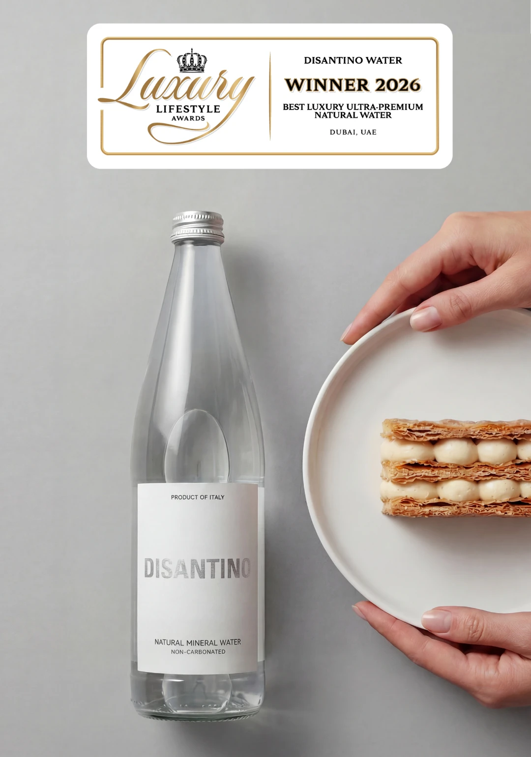 A split-screen marketing image. On the left, a majestic waterfall flows down a green cliff. On the right, an overhead view of a Disantino water bottle next to a hand holding a plate with a layered pastry. A central gold badge reads "Luxury Lifestyle Awards Winner 2026: Best Luxury Ultra-Premium Natural Water, Dubai, UAE."
