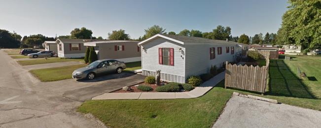 Mobile home with wooden fenced yard and car in driveway