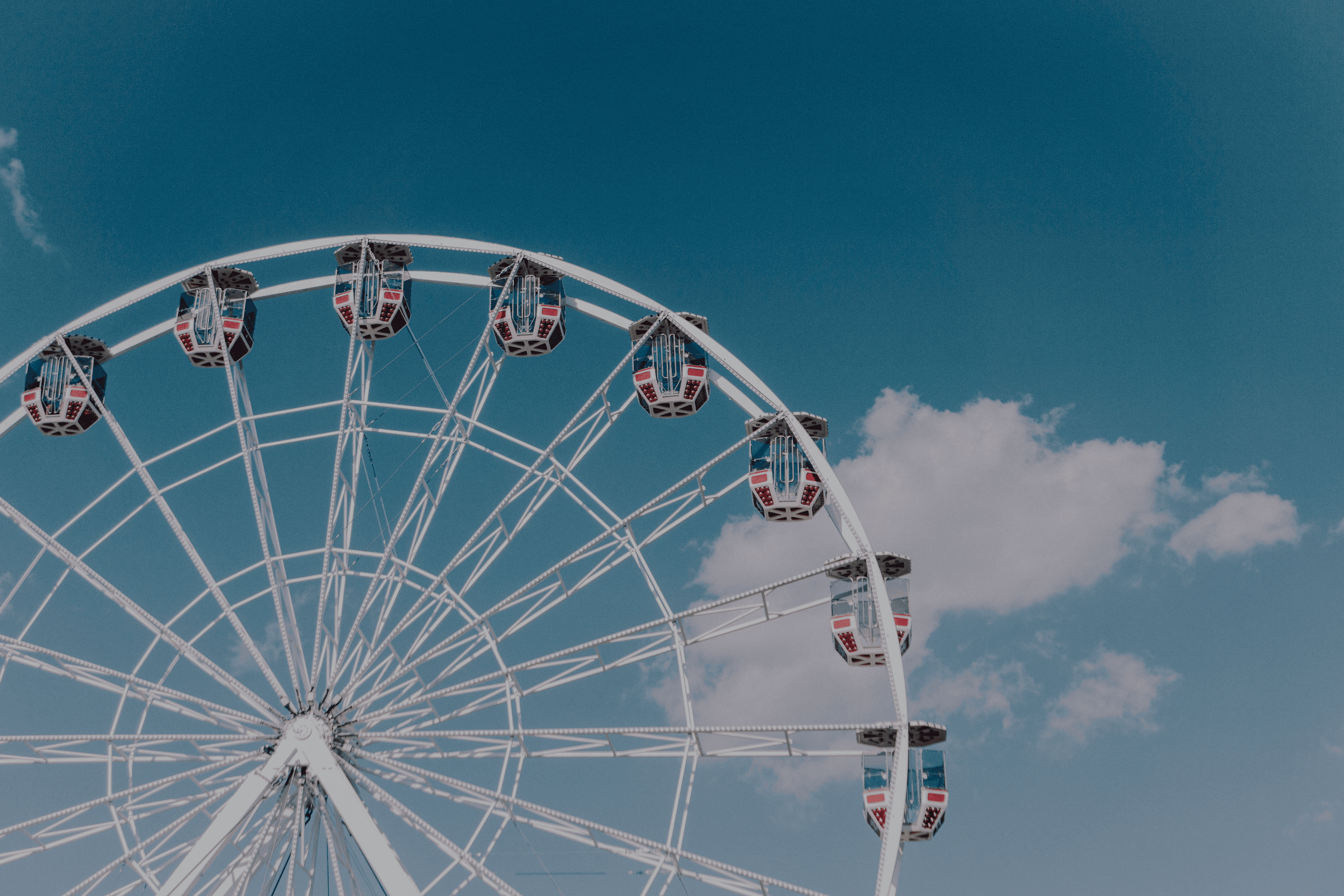 Person hanging upside down from orange playground bars against a bright blue sky.