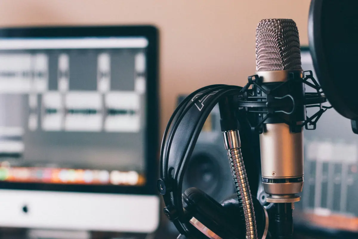 Radio Branding, Tonstudio mit iMac mit Audio Software und einem Mikrofon mit Kopfhörern davor.