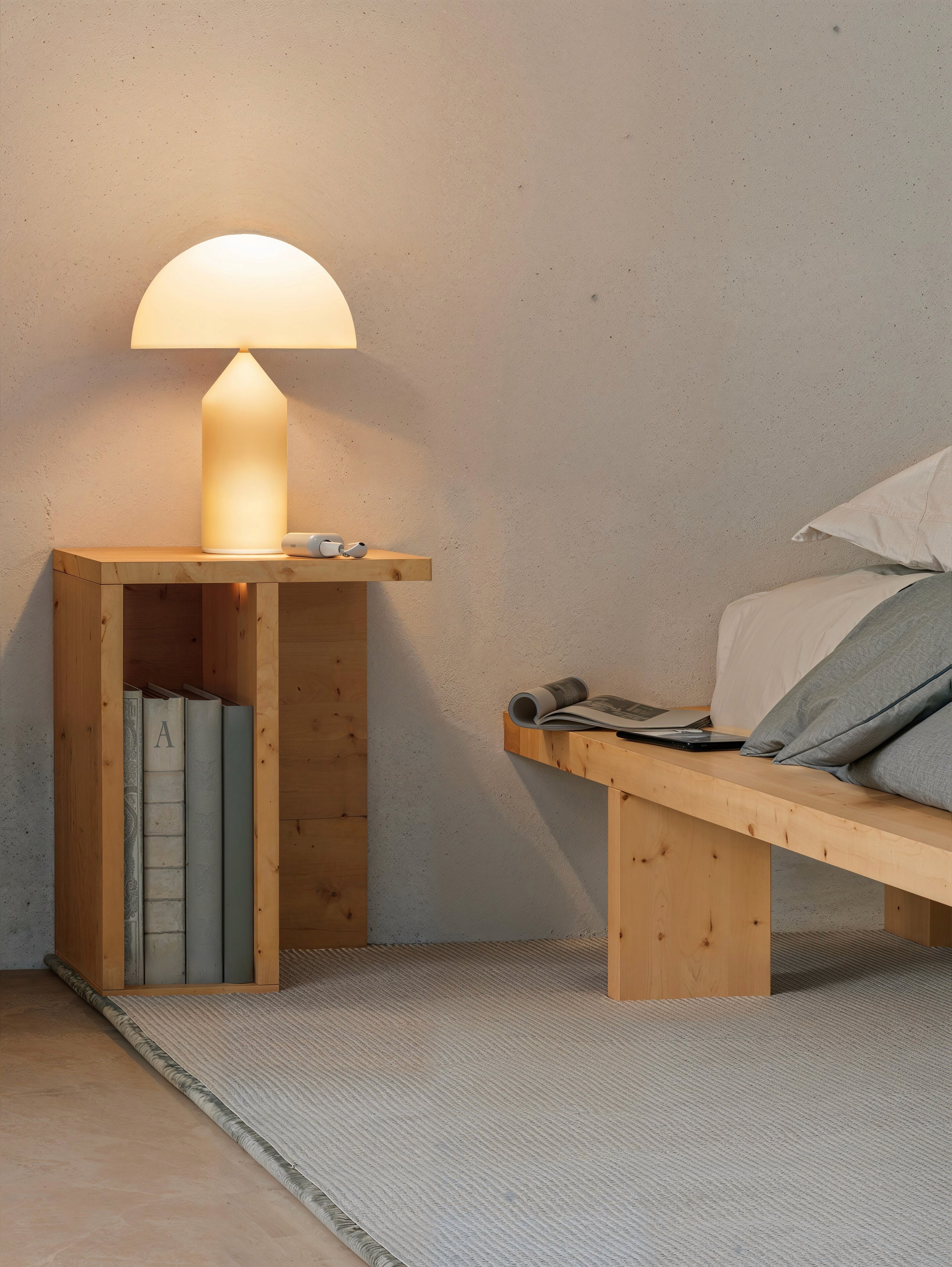 Child walking on a wooden beam with a large tree and swing nearby in a courtyard of modern wooden houses, while another person adjusts a bicycle.