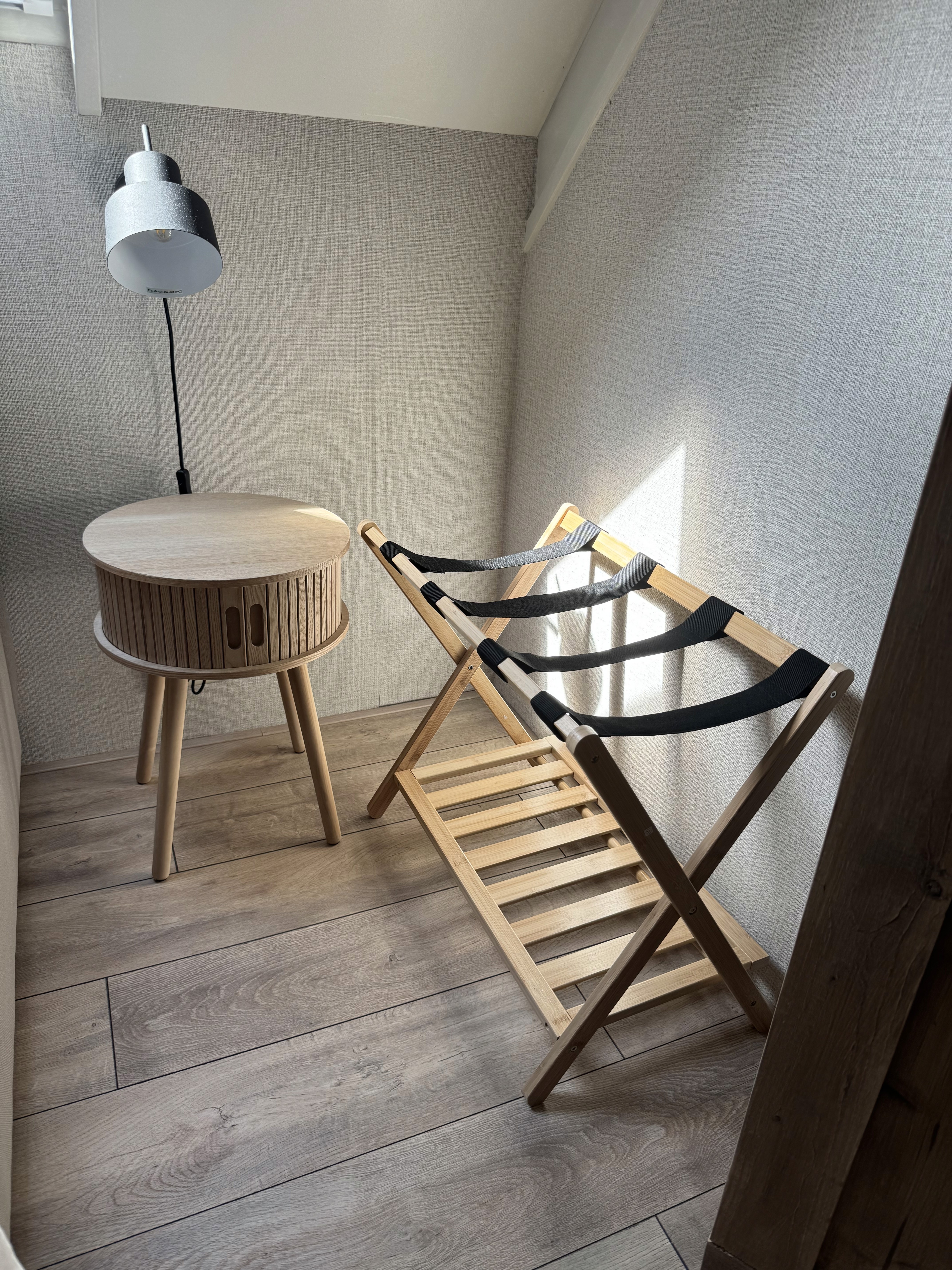 Slaapkamer details met houten nachtkastje en inklapbaar kofferrek.