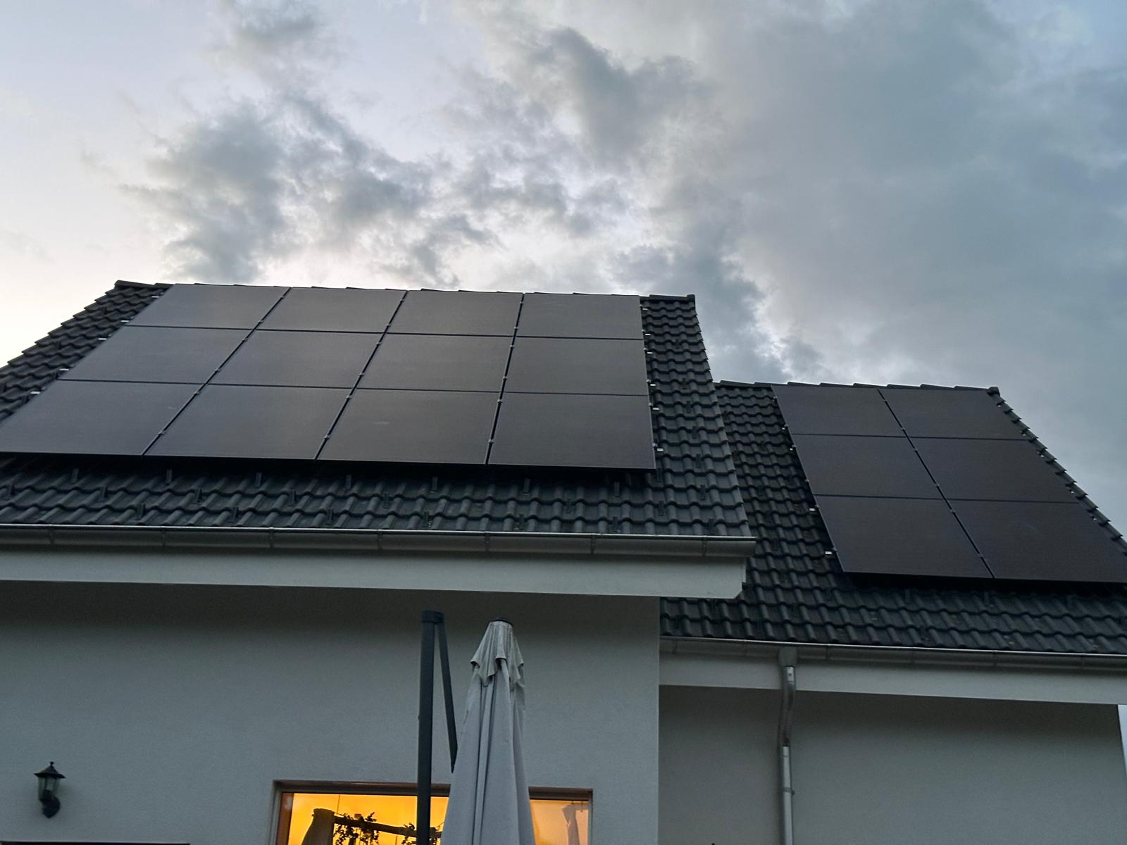 Modernes weisses Einfamilienhaus in Amlikon mit einer 15 kWh Photovoltaikanlage auf dem dunklen Ziegeldach bei strahlendem Sonnenschein.