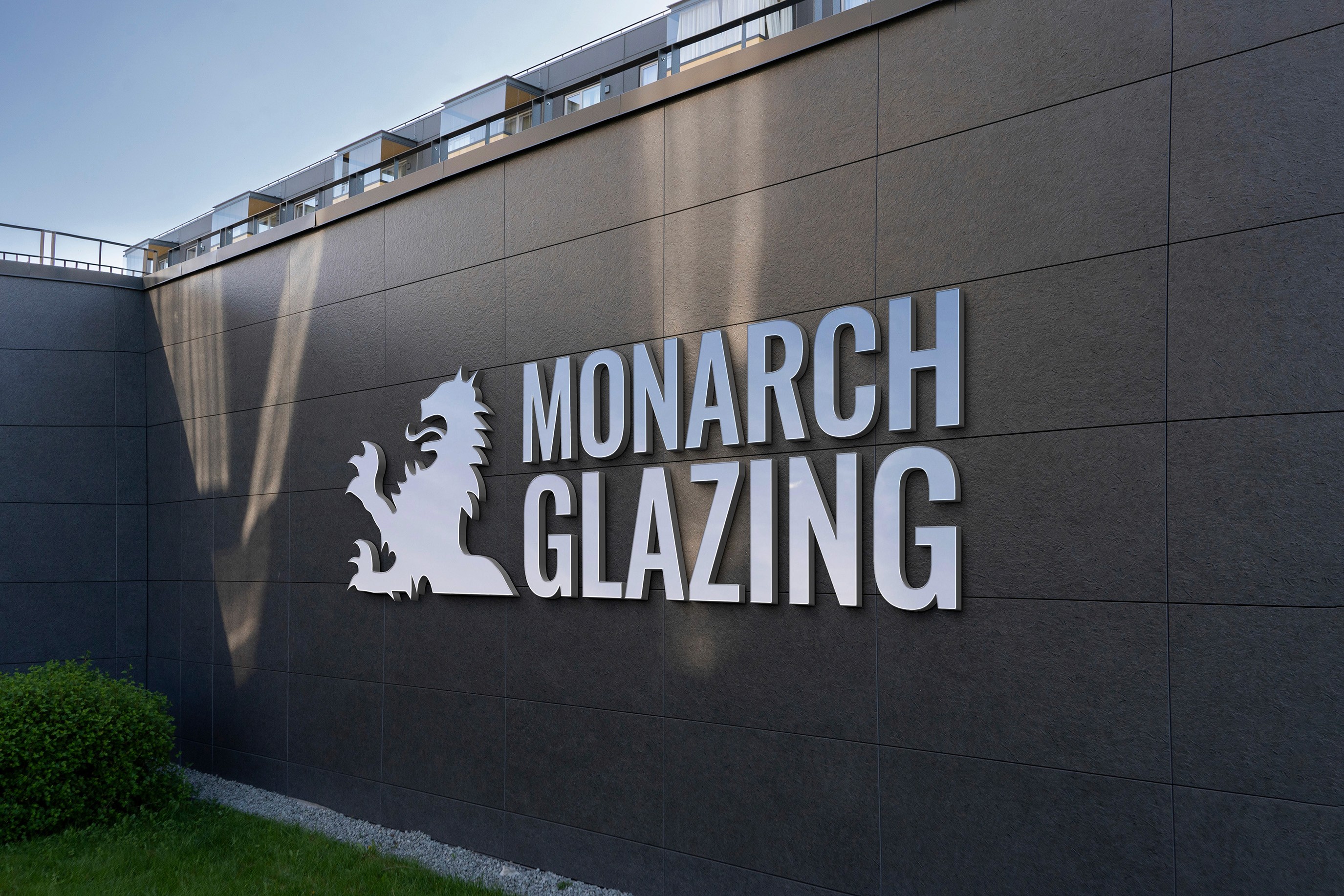 signage mockup of Monarch Glazing's logo in aluminum on wall