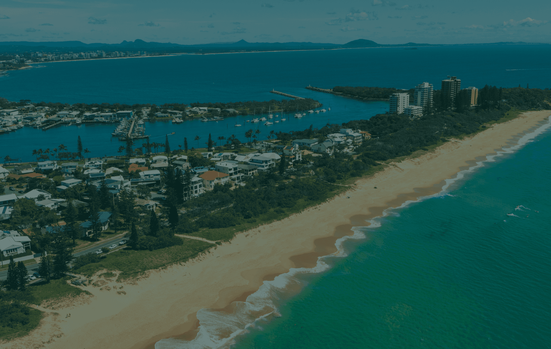 Coastal town with beach, harbor, apartments, and ocean.