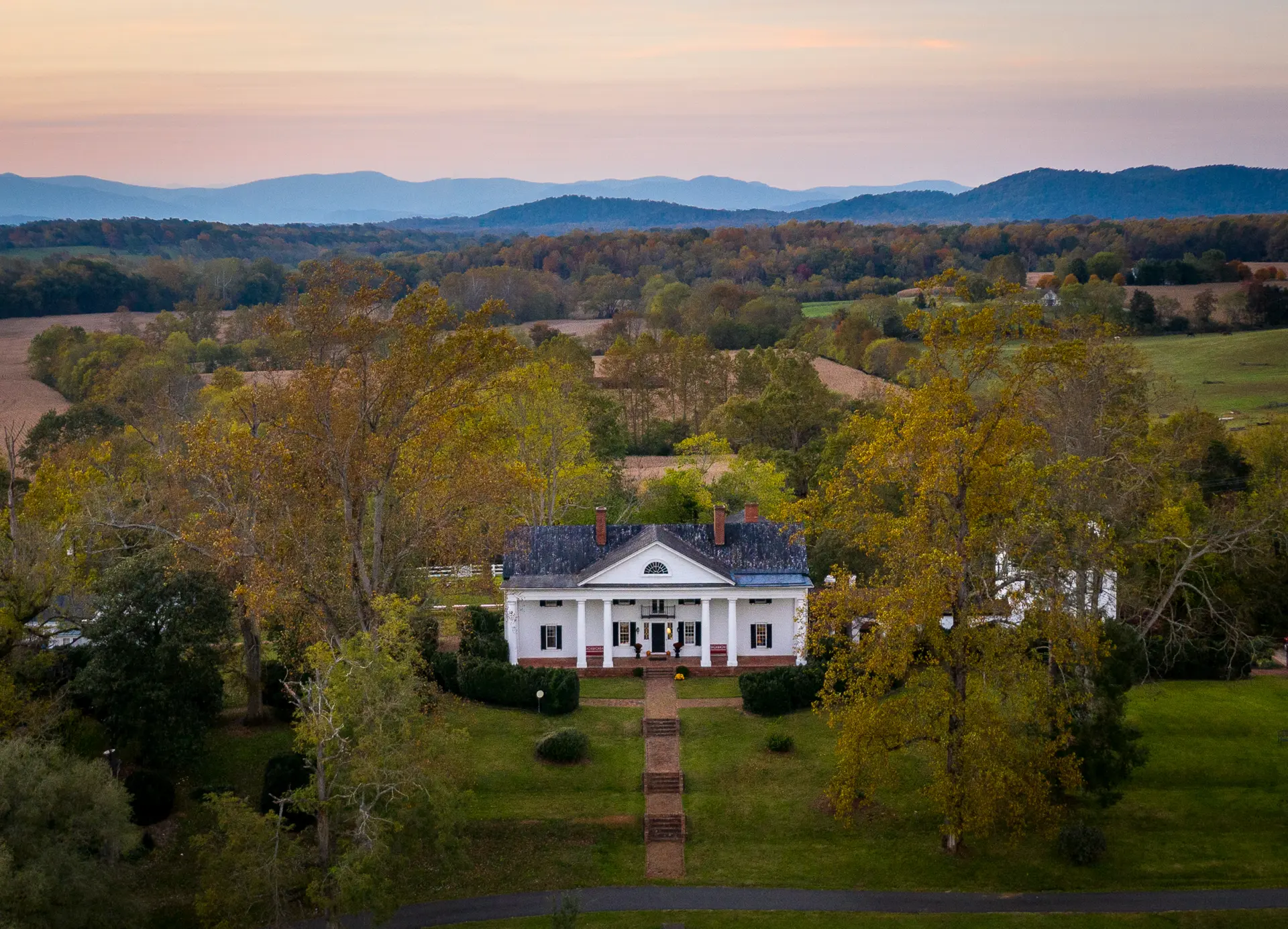 A corner building with a modern façade, featuring large windows and a welcoming entrance, surrounded by greenery.