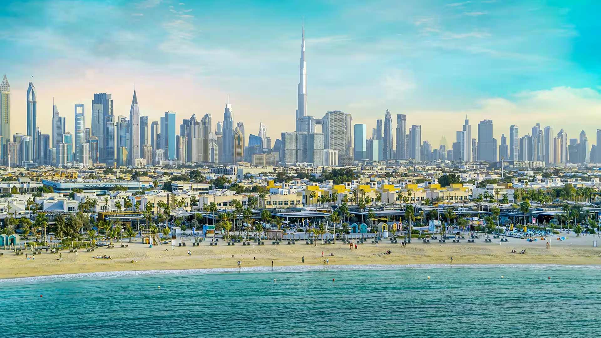 Wide view of the Dubai skyline and Burj Khalifa from the beach, highlighting the city's scale near the Majan area.