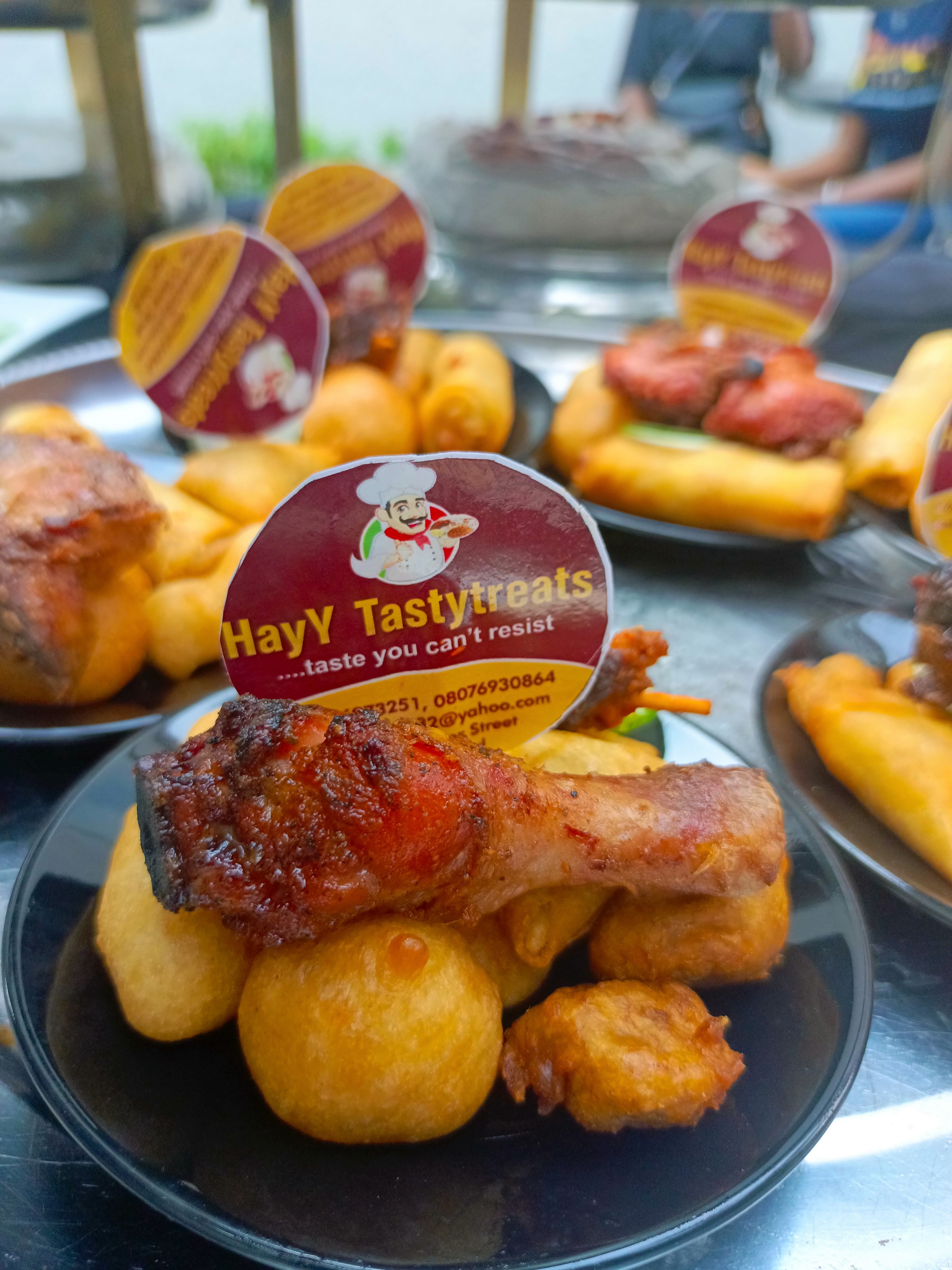 A plate of HayY TastyTreats, featuring roasted chicken, fried plantains, and spring rolls.