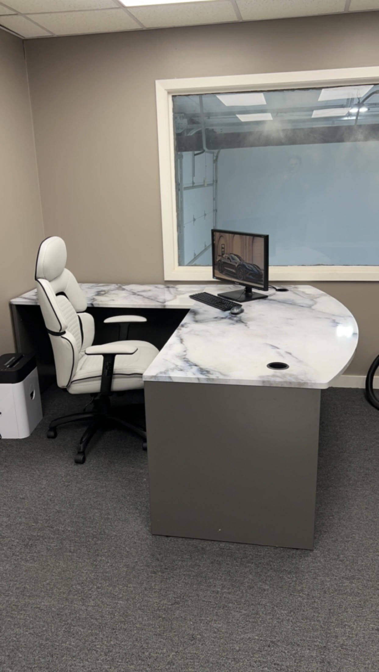 A modern office desk with a computer monitor and office supplies on the countertop.