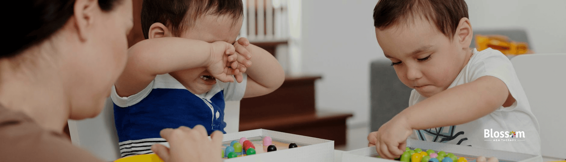 Two children with autism playing with colorful beads while an RBT assists them at a table in VA.