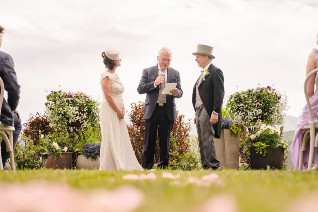 An officiant reads from a paper while standing between the bride and groom during an outdoor ceremony at a Chaparral Ranch Wedding.