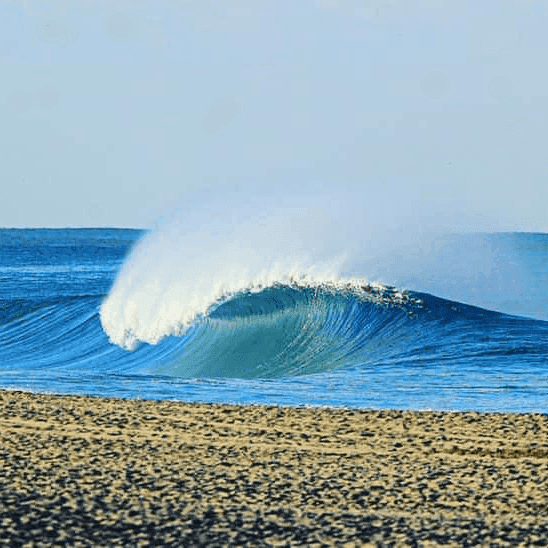 Large wave crashing on sandy beach – surfboard rental in sayulita.