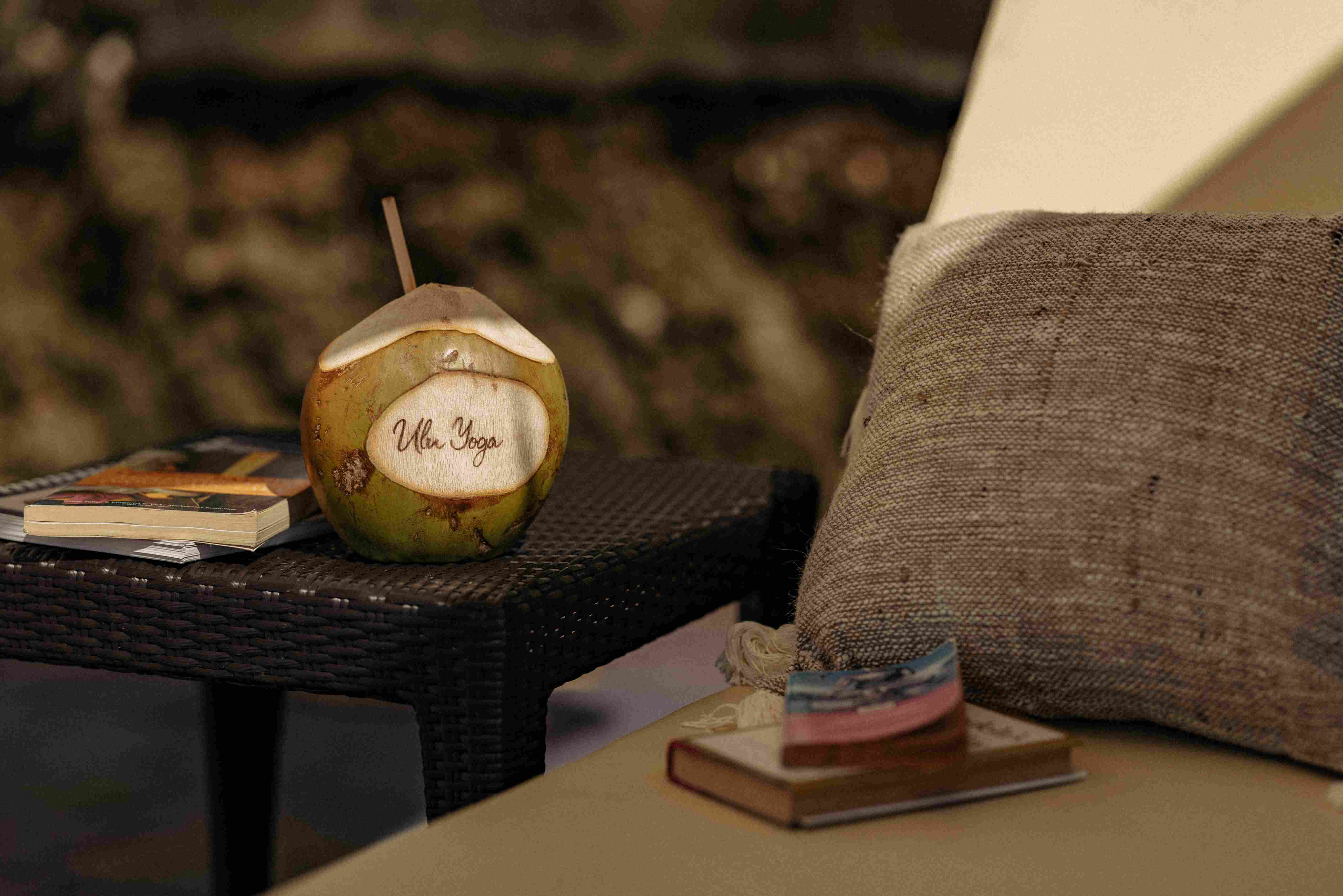 Fresh coconut with carved Ulu Yoga logo and cushion for relaxation at the yoga retreat center.