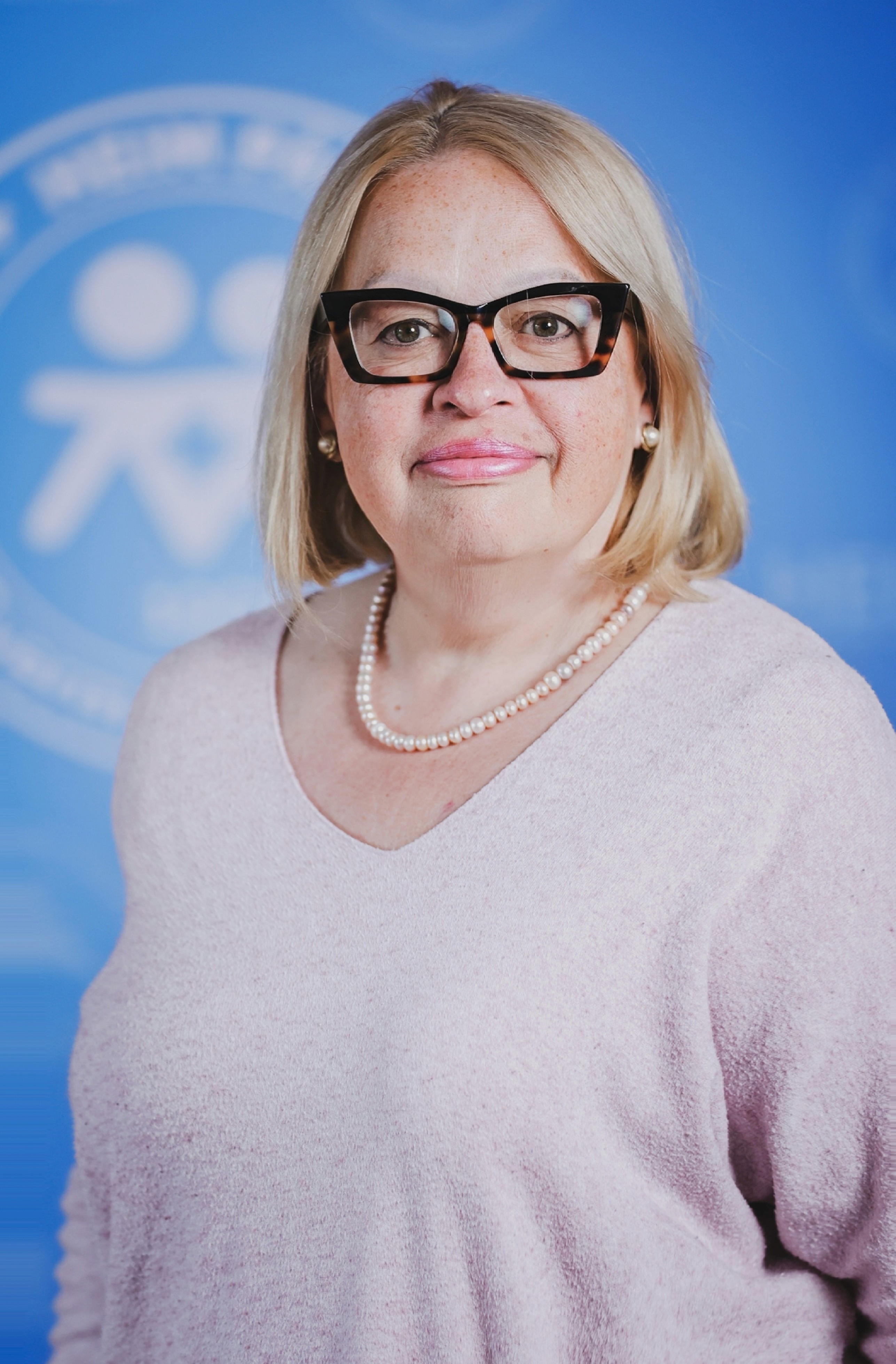 Szemüveges szőke nő rózsaszín pulcsiban