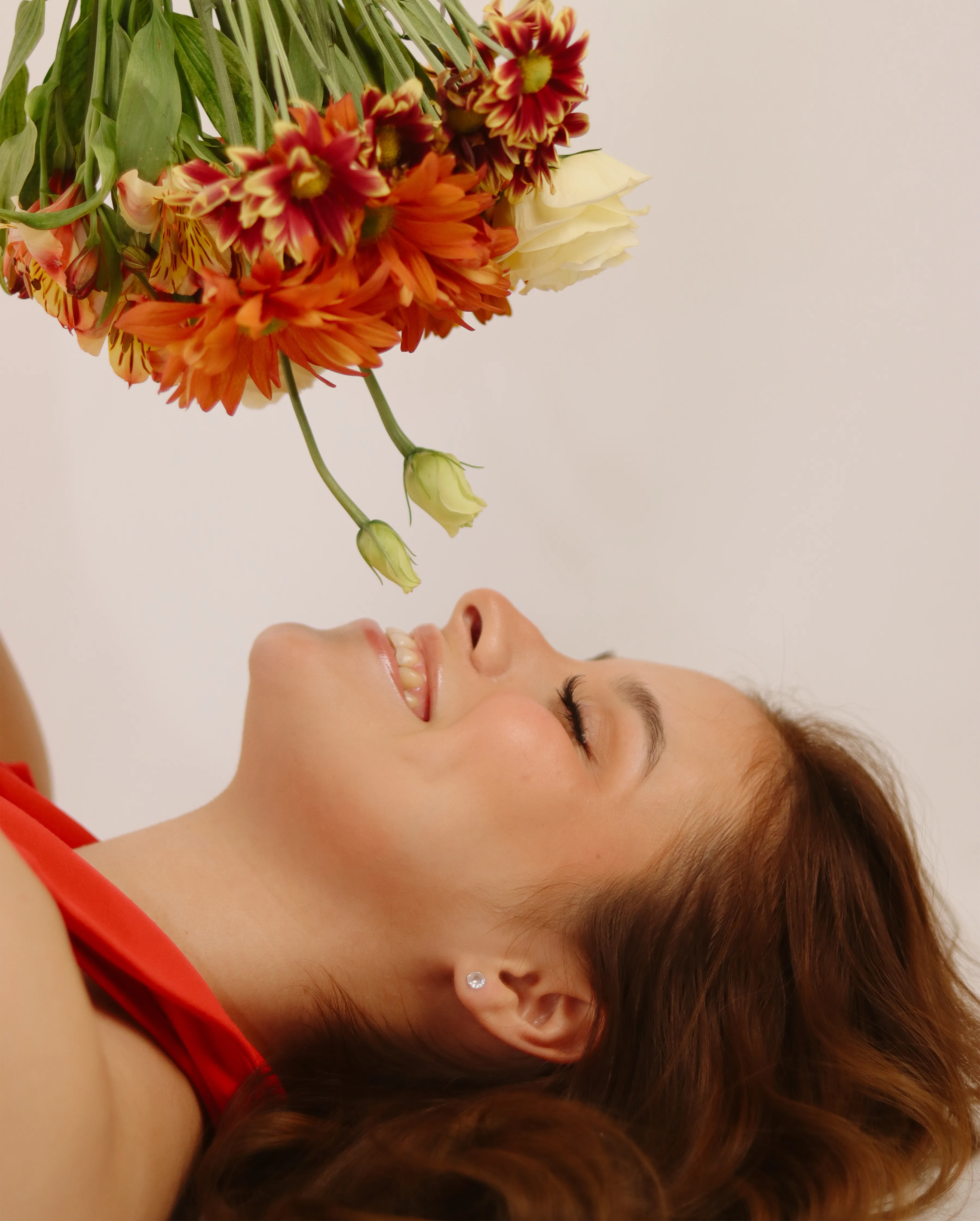 Mujer sonriendo mientras sostiene un ramo invertido de flores