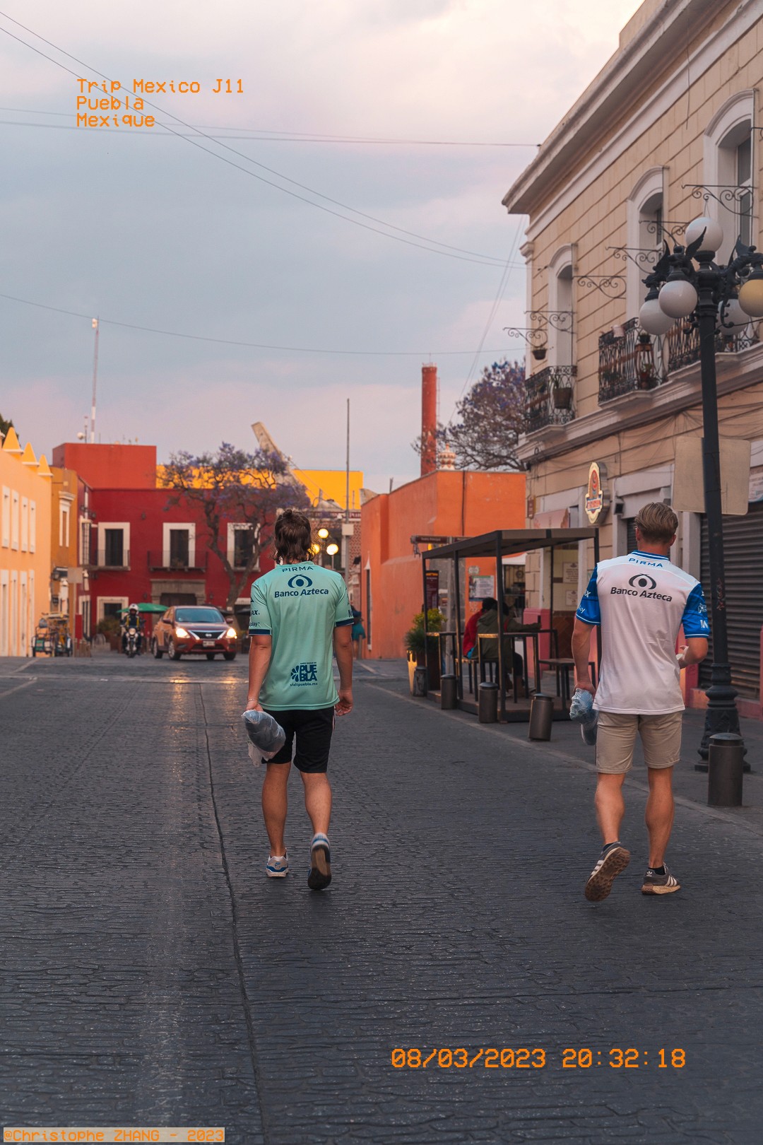 Deux passants marchent dans une rue colorée de Puebla au soir